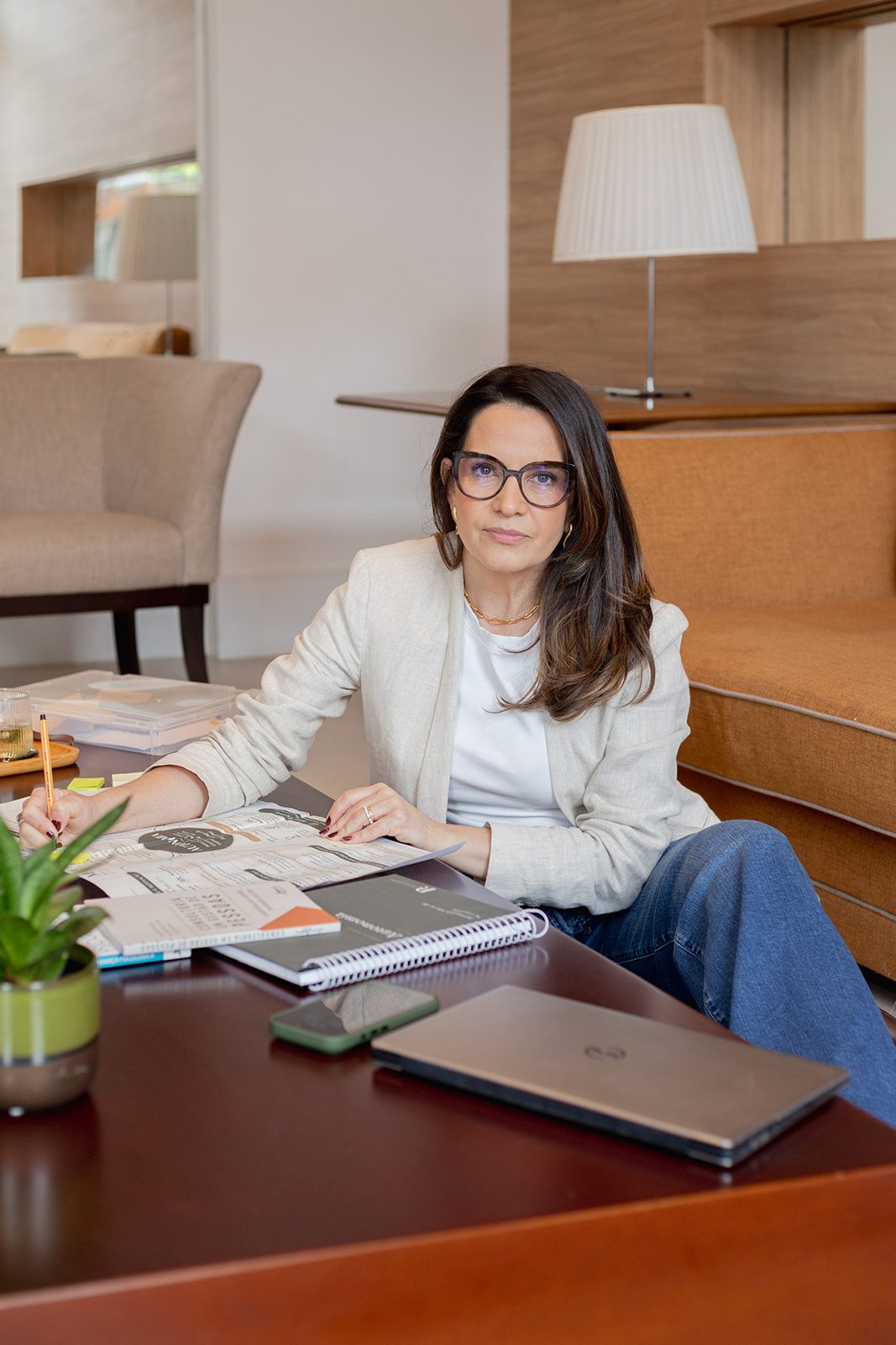 Patrícia Ribeiro sorrindo à mesa, com materiais de trabalho